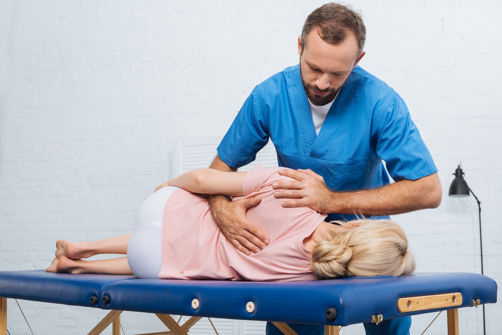 portrait of chiropractor massaging back of patient that lying on massage table in hospital
